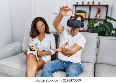 Middle Age Man And Woman Couple Using Vr Goggles Sitting On Sofa With Dog At Home