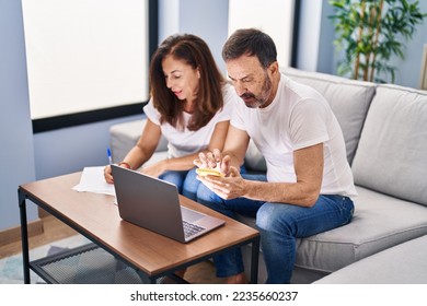 Middle age man and woman couple accounting using smartphone and laptop at home - Powered by Shutterstock