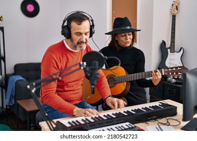 Middle Age Man And Woman Musicians Playing Guitar And Keyboard Piano Singing Song At Music Studio