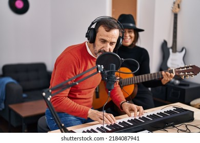 Middle Age Man And Woman Musicians Playing Guitar And Keyboard Piano Singing Song At Music Studio