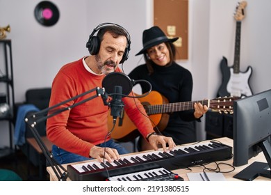 Middle Age Man And Woman Musicians Playing Guitar And Keyboard Piano Singing Song At Music Studio