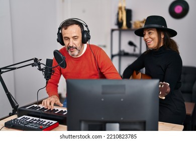 Middle Age Man And Woman Musicians Playing Guitar And Keyboard Piano Singing Song At Music Studio