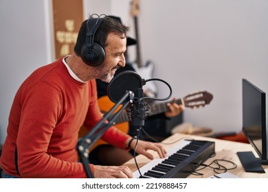 Middle Age Man And Woman Musicians Playing Guitar And Keyboard Piano Singing Song At Music Studio