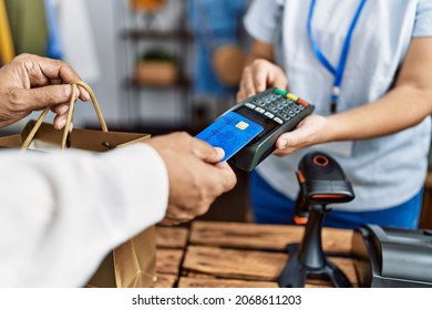 Middle Age Man And Woman Using Credit Card And Data Phone Paying At Clothing Store