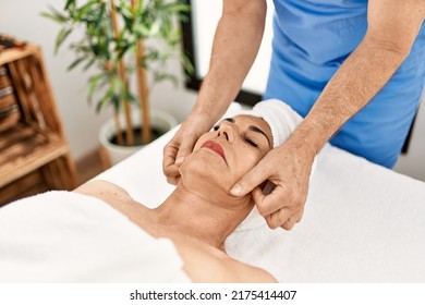 Middle Age Man And Woman Wearing Therapist Uniform Having Facial Massage Session At Beauty Center