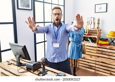 Middle age man working as manager at retail boutique doing stop gesture with hands palms, angry and frustration expression 