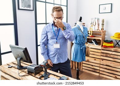 Middle age man working as manager at retail boutique tired rubbing nose and eyes feeling fatigue and headache. stress and frustration concept. 