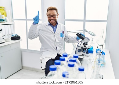 Middle Age Man Working At Scientist Laboratory Smiling With An Idea Or Question Pointing Finger With Happy Face, Number One 