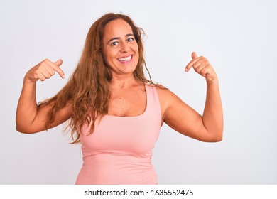 Middle age mature woman standing over white isolated background looking confident with smile on face, pointing oneself with fingers proud and happy.