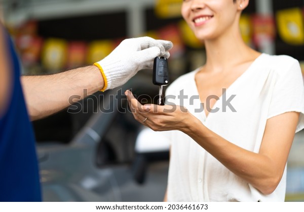 Middle age mechanic man with beard gives the car
key to female customer at Car maintenance station and automobile
service garage