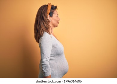 Middle Age Pregnant Woman Expecting Baby At Aged Pregnancy Looking To Side, Relax Profile Pose With Natural Face With Confident Smile.