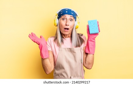 Middle Age Pretty Woman Looking Surprised And Shocked, With Jaw Dropped Holding An Object. Scourer Cleaner