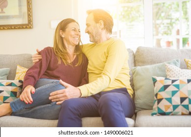 Middle age romantic couple sitting on the sofa at home