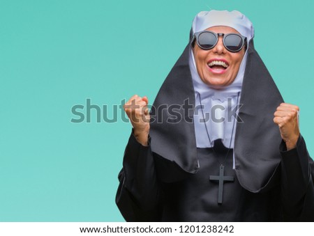 Middle age senior catholic nun woman wearing sunglasses over isolated background celebrating surprised and amazed for success with arms raised and open eyes. Winner concept.