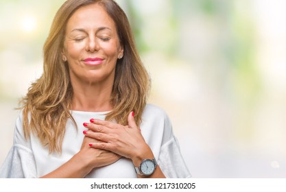 Middle age senior hispanic woman over isolated background smiling with hands on chest with closed eyes and grateful gesture on face. Health concept. - Powered by Shutterstock