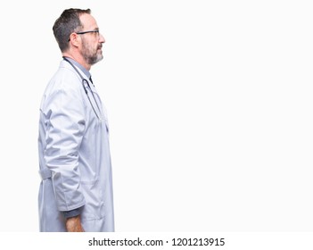 Middle age senior hoary doctor man wearing medical uniform isolated background looking to side, relax profile pose with natural face with confident smile.