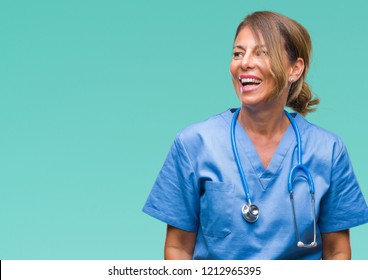 Middle age senior nurse doctor woman over isolated background looking away to side with smile on face, natural expression. Laughing confident.
