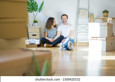 Middle age senior romantic couple in love sitting on the apartment floor with cardboard boxes around and smiling happy for moving to a new home - Powered by Shutterstock