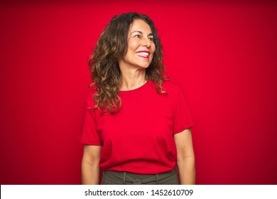 Middle age senior woman with curly hair over red isolated background looking away to side with smile on face, natural expression. Laughing confident. - Shutterstock ID 1452610709