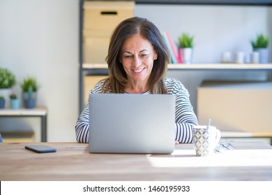 Middle Age Senior Woman Sitting At The Table At Home Working Using Computer Laptop With A Happy And Cool Smile On Face. Lucky Person.
