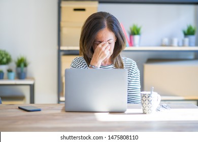 Middle Age Senior Woman Sitting At The Table At Home Working Using Computer Laptop Tired Rubbing Nose And Eyes Feeling Fatigue And Headache. Stress And Frustration Concept.