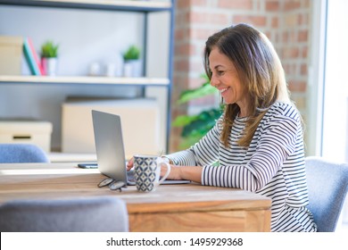 Middle age senior woman sitting at the table at home working using computer laptop with a happy face standing and smiling with a confident smile showing teeth - Shutterstock ID 1495929368