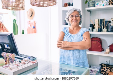 Middle age shop assistance woman working at the counter of retail shop smiling happy