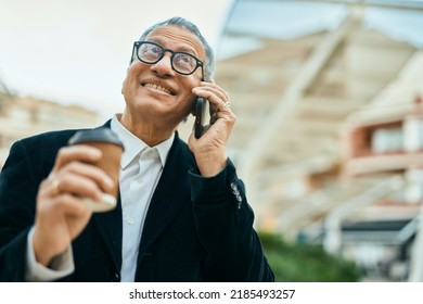 Middle Age Southeast Asian Man Speaking On The Phone And Drinking A Cup Of Coffee At The City