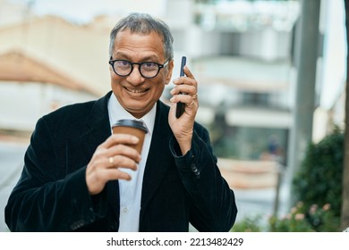 Middle Age Southeast Asian Man Speaking On The Phone And Drinking A Cup Of Coffee At The City