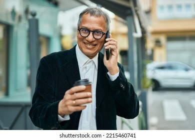 Middle Age Southeast Asian Man Speaking On The Phone And Drinking A Cup Of Coffee At The City