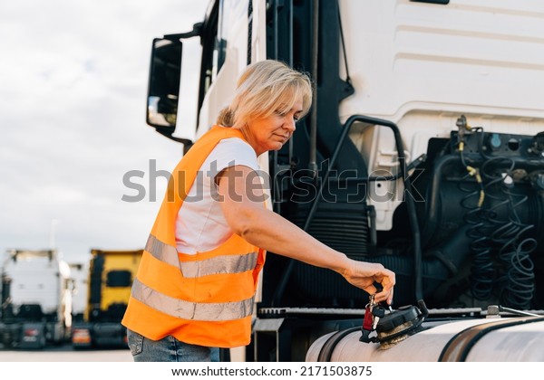 Middle\
age truck driver woman opens gas tank with keys\
