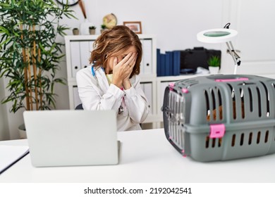 Middle Age Veterinarian Woman Working At Pet Clinic With Sad Expression Covering Face With Hands While Crying. Depression Concept. 