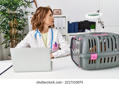 Middle Age Veterinarian Woman Working At Pet Clinic Looking To Side, Relax Profile Pose With Natural Face With Confident Smile. 