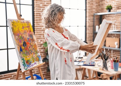 Middle age woman artist looking draw at art studio - Powered by Shutterstock