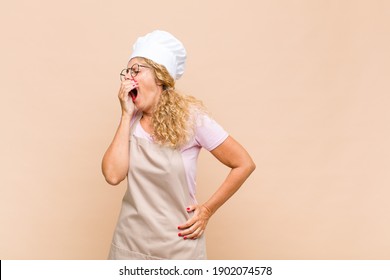 middle age woman baker yawning lazily early in the morning, waking and looking sleepy, tired and bored