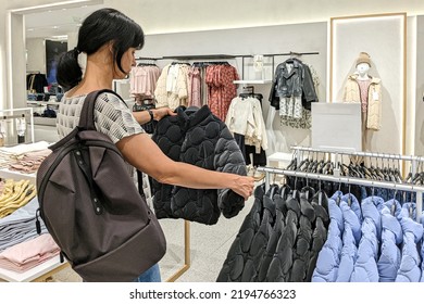 Middle Age Woman Choosing New Clothes In Children Clothing Store Inside Shopping Mall