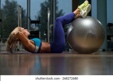 Middle Age Woman Exercising Abdominals On Exercise Ball In Fitness Club