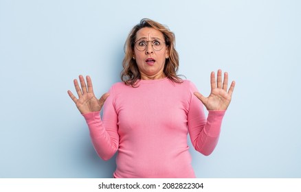 middle age woman feeling stupefied and scared, fearing something frightening, with hands open up front saying stay away
