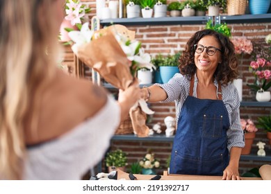 Middle Age Woman Florist Giving Bouquet Of Flowers To Client At Flower Shop