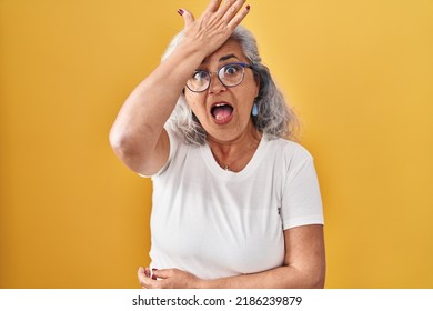 Middle Age Woman With Grey Hair Standing Over Yellow Background Surprised With Hand On Head For Mistake, Remember Error. Forgot, Bad Memory Concept. 