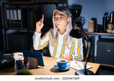 Middle Age Woman With Grey Hair Working At The Office At Night Pointing Finger Up With Successful Idea. Exited And Happy. Number One. 