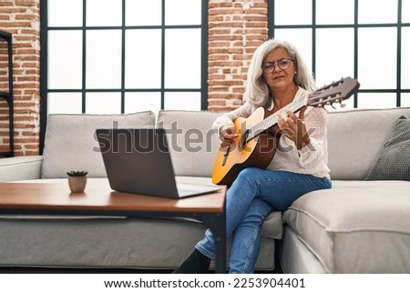 Middle age woman having online guitar class at home