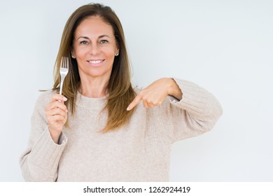 Middle Age Woman Holding Silver Fork Metal Over Isolated Background With Surprise Face Pointing Finger To Himself