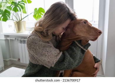 Middle Age Woman Hugging Her Beloved Wirehaired Vizsla Dog At Home. Female Owner Kissing And Embracing Her Lovely Pet In Living Room. Animal Therapy, Stress Relief Concept. 