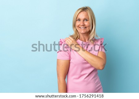 Middle age woman isolated on blue background celebrating a victory