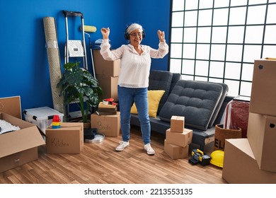 Middle Age Woman Listening To Music And Dancing At New Home