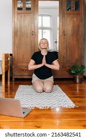 Middle Age Woman Mediating And Doing Yoga At Home With Laptop Online Class