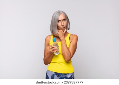 middle age woman with mouth and eyes wide open and hand on chin, feeling unpleasantly shocked, saying what or wow. fitness concept - Powered by Shutterstock