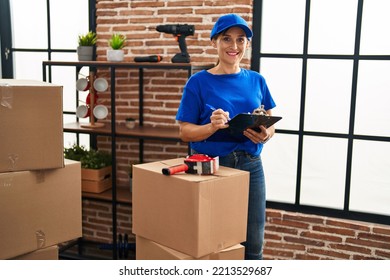 Middle Age Woman Moving Worker Writing On Checklist At New Home