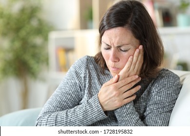 Middle Age Woman In Pain Suffering Toothache Touching Face Sitting On A Couch At Home